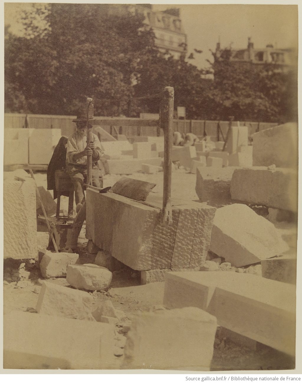 Tailleur de pierre à l’établi, blocs dressés — photographie Atget